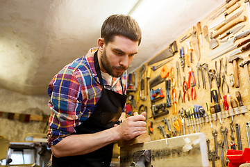 Image showing carpenter working with plane and wood at workshop