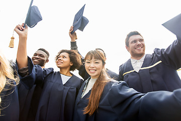 Image showing happy students or bachelors waving mortar boards