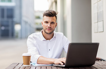 Image showing man with laptop and coffee at city cafe