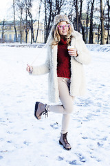 Image showing young pretty teenage hipster girl outdoor in winter snow park having fun drinking coffee, warming up happy smiling, lifestyle people concept