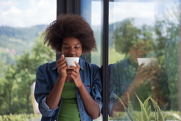 Image showing African American woman drinking coffee looking out the window