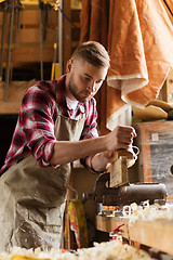 Image showing carpenter working with plane and wood at workshop