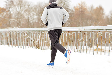 Image showing man running along snow covered winter bridge road