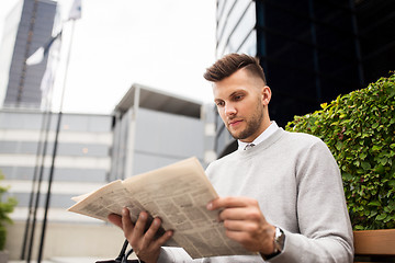 Image showing man reading newspaper on city street bench