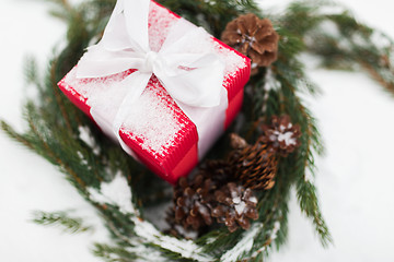 Image showing close up of christmas gift and fir wreath on snow