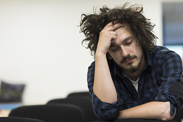 Image showing A student sits alone  in a classroom