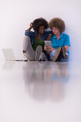 Image showing multiethnic couple sitting on the floor with a laptop and tablet