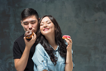 Image showing Young asian couple enjoy eating of sweet colorful donut