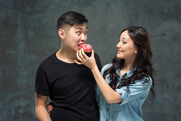 Image showing Young asian couple enjoy eating of sweet colorful donut