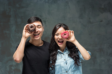 Image showing Young asian couple enjoy eating of sweet colorful donut