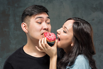 Image showing Young asian couple enjoy eating of sweet colorful donut