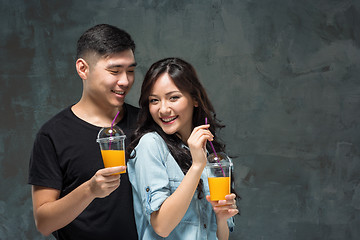 Image showing A young pretty Asian couple with a glasses of Orange juice