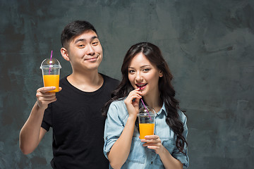 Image showing A young pretty Asian couple with a glasses of Orange juice