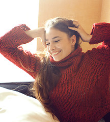 Image showing young pretty real woman in sweater and scarf all over her face smiling