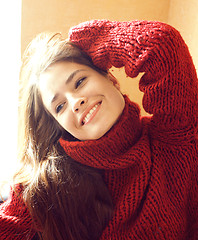 Image showing young pretty real woman in sweater and scarf all over her face smiling