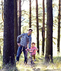 Image showing father learning his son to ride on bicycle outside