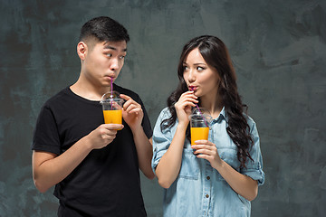 Image showing A young pretty Asian couple with a glasses of Orange juice