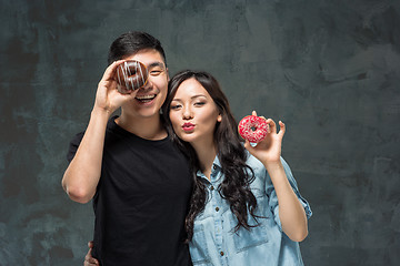 Image showing Young asian couple enjoy eating of sweet colorful donut