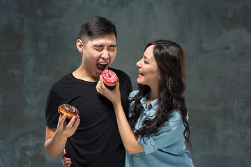 Image showing Young asian couple enjoy eating of sweet colorful donut