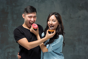 Image showing Young asian couple enjoy eating of sweet colorful donut