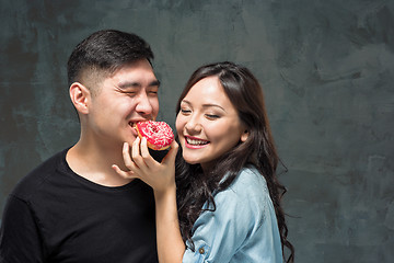 Image showing Young asian couple enjoy eating of sweet colorful donut