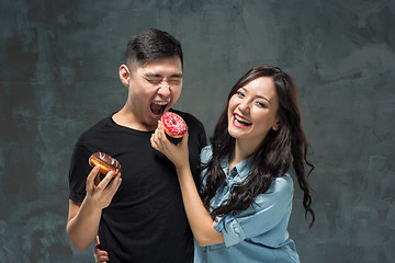 Image showing Young asian couple enjoy eating of sweet colorful donut