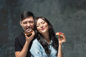 Image showing Young asian couple enjoy eating of sweet colorful donut