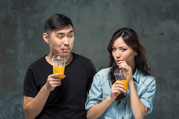 Image showing A young pretty Asian couple with a glasses of Orange juice