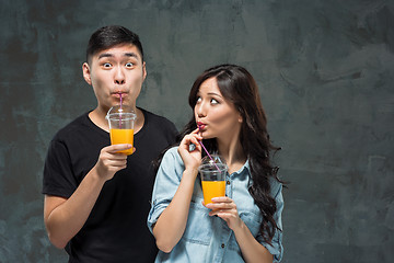 Image showing A young pretty Asian couple with a glasses of Orange juice