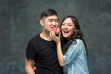 Image showing Young asian couple enjoy eating of sweet colorful donut