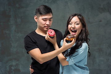 Image showing Young asian couple enjoy eating of sweet colorful donut