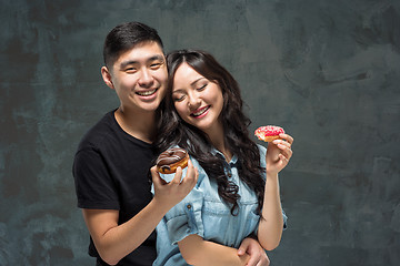 Image showing Young asian couple enjoy eating of sweet colorful donut