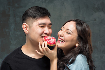 Image showing Young asian couple enjoy eating of sweet colorful donut