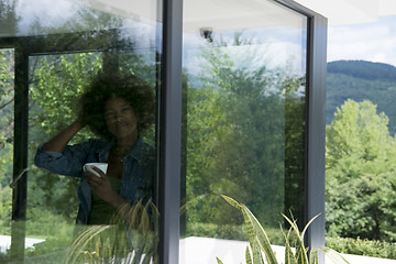 Image showing African American woman drinking coffee looking out the window