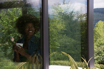 Image showing African American woman drinking coffee looking out the window