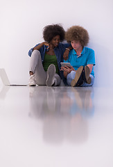 Image showing multiethnic couple sitting on the floor with a laptop and tablet