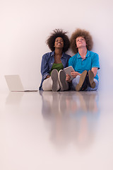 Image showing multiethnic couple sitting on the floor with a laptop and tablet