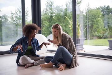 Image showing multiethnic women sit on the floor and drinking coffee