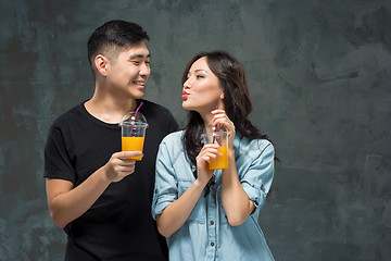 Image showing A young pretty Asian couple with a glasses of Orange juice