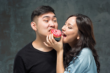 Image showing Young asian couple enjoy eating of sweet colorful donut