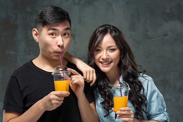 Image showing A young pretty Asian couple with a glasses of Orange juice