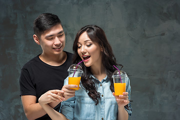 Image showing A young pretty Asian couple with a glasses of Orange juice