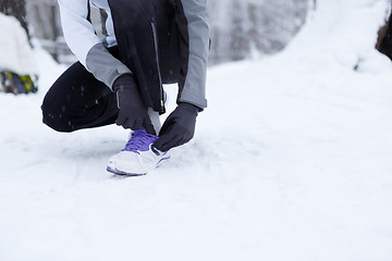 Image showing Girl corrects shoes in winter