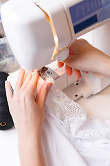 Image showing Seamstress scribbles cloth on sewing-machine