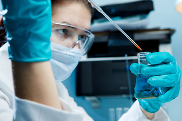 Image showing Woman with protective glasses , flask