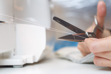 Image showing Seamstress cuts with scissors thread