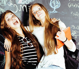 Image showing back to school after summer vacations, two teen real girls in classroom with blackboard painted together, lifestyle real people concept