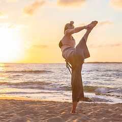 Image showing Woman practicing yoga on sea beach at sunset.