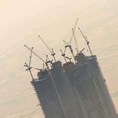 Image showing Skyscraper construction site with cranes on top of buildings.