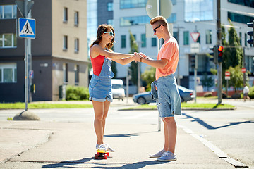 Image showing teenage couple riding skateboards on city street